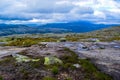 Tourist girl stands on the edge of a cliff 984 meters high above Lysefjorden, where famous Kjeragbolten stuck nearby. Norway