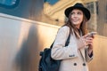 Tourist girl stands on the platform of railway station near passenger train car with mobile phone in hands. Royalty Free Stock Photo