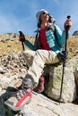 A tourist girl wearing sunglasses down jacket and hat with a backpack and mountain equipment with handles for tracking Royalty Free Stock Photo