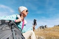 A tourist girl wearing sunglasses down jacket and hat with a backpack and mountain equipment with handles for tracking Royalty Free Stock Photo