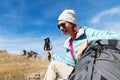 A tourist girl wearing sunglasses down jacket and hat with a backpack and mountain equipment with handles for tracking Royalty Free Stock Photo