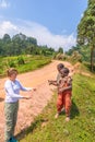 A tourist giving some kids in old ragged clothes in a rural area candy, Lake Mutanda, Uganda.