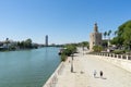 Tourist Golden Tower in Sevilla with the Guadalquivir river and people walking on the corridor path.