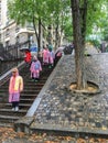 Tourist group in colorful raincoats descends outdoor stairs near Montmartre funicular