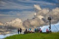 Tourist group takes a break on a bench next to a wooden cross with Jesus at a crucifix on their way to the summit Royalty Free Stock Photo