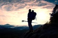 Tourist guide with pole in hand. Hiker with sporty backpack stand on rocky view point above misty valley. Sunny spring daybreak Royalty Free Stock Photo