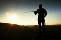 Tourist guide show the right way with pole in hand. Hiker with sporty backpack stand on rocky view point above misty valley. Sunny Royalty Free Stock Photo