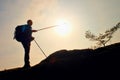 Tourist guide show the right way with pole in hand. Hiker with sporty backpack stand on rocky view point above misty valley. Royalty Free Stock Photo