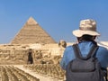 Tourist with a hat photographing a pyramid in Egypt