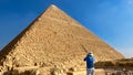 Tourist with a hat photographing a pyramid in Egypt