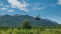 A tourist helicopter comes in to land on a green meadow.