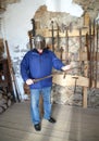 A tourist with a helmet on his head holds a knight`s sword in his hand. Shaaken Castle, XIII century. Kaliningrad region Royalty Free Stock Photo
