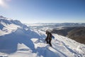 Tourist hiker climber in winter clothing with backpack climbing dangerous rocky steep mountain slope covered with deep snow, white