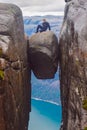 The tourist hiker man sitting on top of Kjeragbolten - the most dangerous stone in the world. Norway Royalty Free Stock Photo