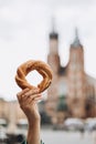 Tourist is holding prezel, traditional polish snack on the Market square in Krakow. Traveling Europe in spring. Food