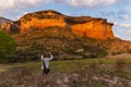 Tourist holding smart phone and taking photo at scenic cliff illuminated by sunset light in the majestic Golden Gate Highlands Nat