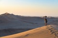 Tourist holding smart phone and taking photo at scenic sand dunes illuminated by sunset light in the Namib desert, Namib Naukluft Royalty Free Stock Photo