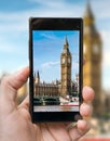 Tourist holds smartphone in hand and photographing Big Ben in London