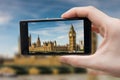 Tourist holds smartphone in hand and photographing Big Ben in London