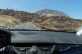 Tourist inside rent a car, driving with control speed, traveling at El Teide, Tenerife. Dashboard of Automobile in Volcano asphalt