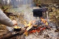 Tourist kettle on camp fire with tent on background. hand with stick about fire.a Royalty Free Stock Photo