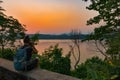 Tourist in Laos Backpacker taking pictures of Mekong River at Sunset