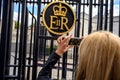 Tourist in London taking close up photos of the Buckingham Palace ER sign, England