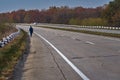 Tourist on the long road goes on the highway with a camera, journey concept background.