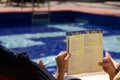 A tourist looking at a food menu next to the pool area in a hotel in Goa, India