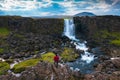 Tourist looking at the Oxarafoss waterfall in Iceland