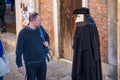 A tourist looking at a street performer with Bauta mask in Venice, Italy Royalty Free Stock Photo