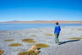 Tourist looking at the stunning landscape of salty frozen lake on the Andes, road trip to the famous Uyuni Salt Flat, travel desti