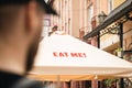 Tourist is looking on a sun umbrella with inscription Eat me of a street cafe.