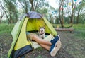 Tourist lying in tent with dog, camping in autumn nature
