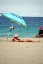 Tourist lying under a colorful beach umbrella on Dania Beach
