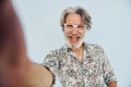 Tourist makes selfie. Senior stylish modern man with grey hair and beard indoors