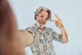 Tourist makes selfie. Senior stylish modern man with grey hair and beard indoors