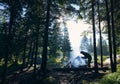 Tourist making fire near tents in forest. Royalty Free Stock Photo