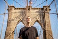 Tourist male model posing in front of Brooklyn Bridge