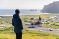 Tourist man enjoy looking view of Reyniskirkja church among the mountain on summer in Vik town