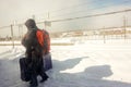 Tourist man hastily walking and holding luggage to keep up the train amid the white snow on floor and cold weather Royalty Free Stock Photo