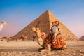 Tourist man with hat riding on camel background pyramid of Egyptian Giza, sunset Cairo, Egypt Royalty Free Stock Photo