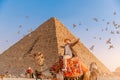 Tourist man with hat riding on camel background pyramid of Egyptian Giza, sunset Cairo, Egypt Royalty Free Stock Photo