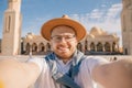 Tourist man in hat takes travel selfie photo background El Mina Masjid mosque in Hurghada, Egypt sunlight