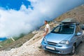Tourist man with his car near Llogara Pass. White fog high in mountains. View from highlands on serpentine road. Albania Royalty Free Stock Photo