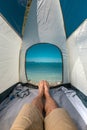 Tourist Man Lying In Tent With A View Of Sea Summer Beach Holiday Vacation Concept. View Of Legs. Point Of View Shot