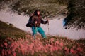 Tourist man standing on the hill field with hiking backpack and sticks in the foreground of pink flowers Royalty Free Stock Photo