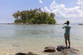 Tourist man standing on the stone in summer season and take a photo beautiful small island in phuket thailand