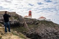 Tourist man takes photos of the lighthouse of Cabo Sao Vicente Cape St Vincent with phone