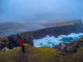 Tourist man taking photo on high cliffs, Faroe Islands, Denmark